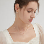 STMG Pearl Daisy Necklace in gold on neck with matching earrings on ear